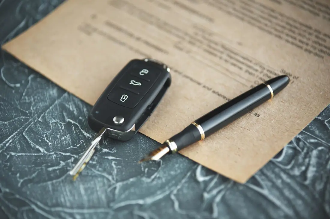 Black car key and money on a signed contract of car sale. Focus on a key. Black car key and money on a signed contract of car sale. Focus on a key.