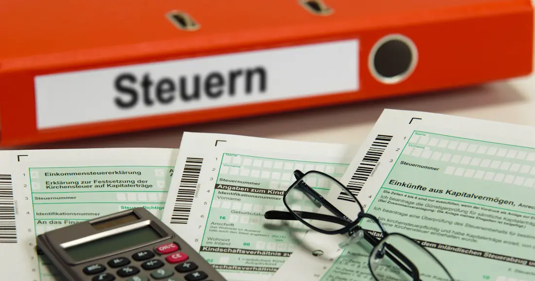 Steuerordner, Formulare und Taschenrechner auf einem Schreibtisch
