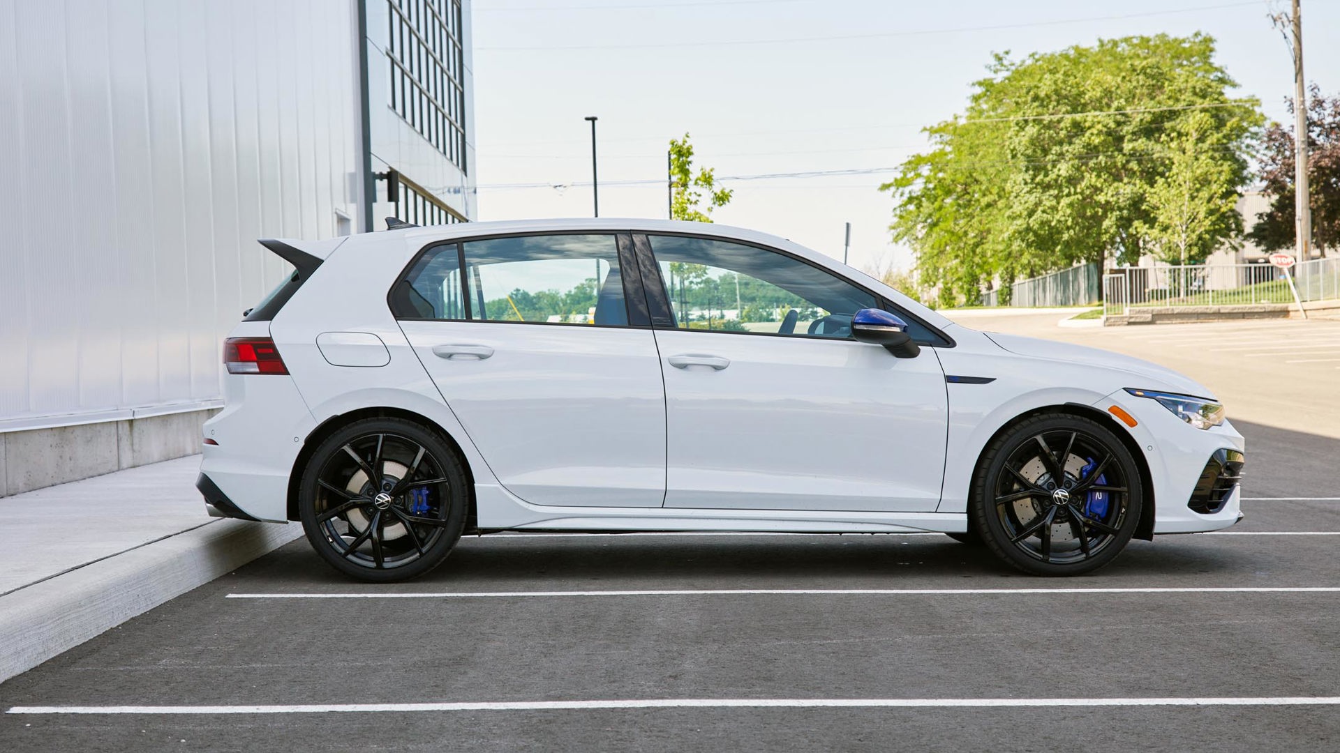 A side profile of a white Volkswagen Golf R parked in a parking lot.