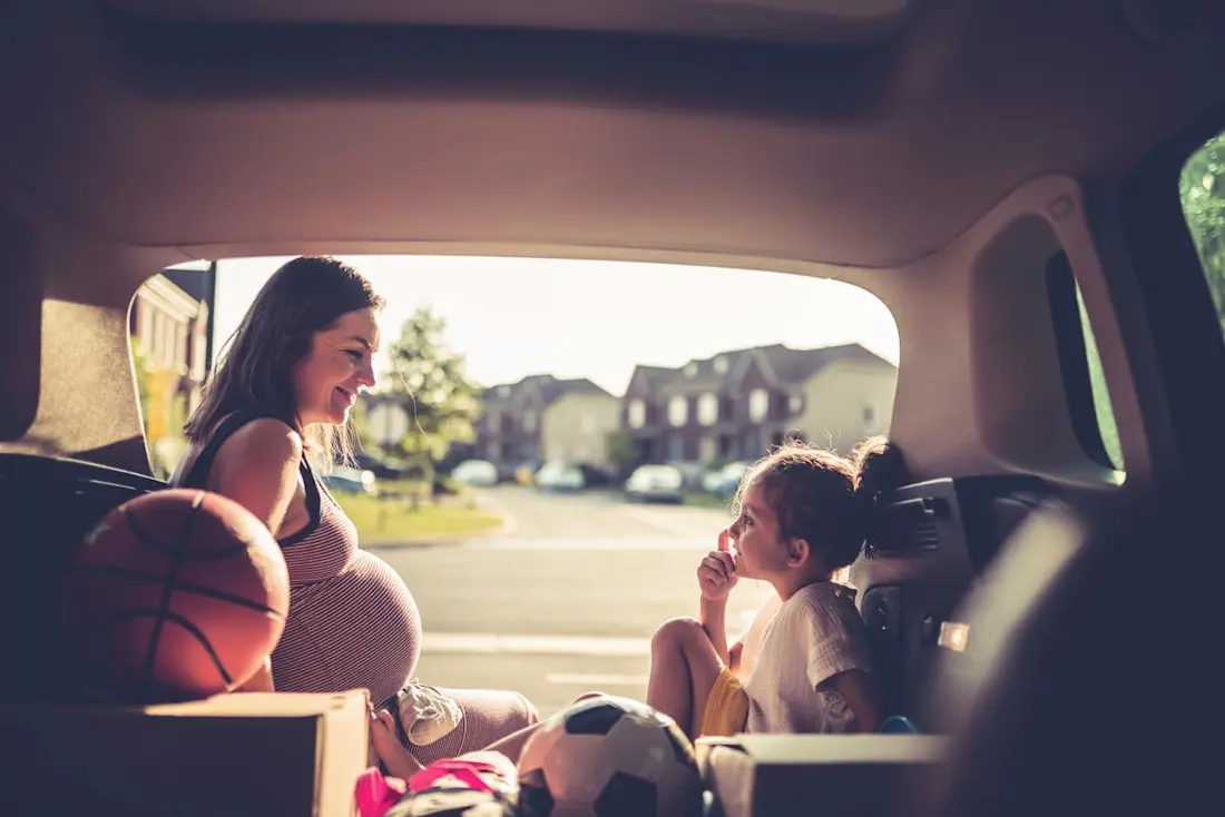 Frau sitzt im Kofferraum mit Kindern  Frau sitzt im Kofferraum mit Kindern