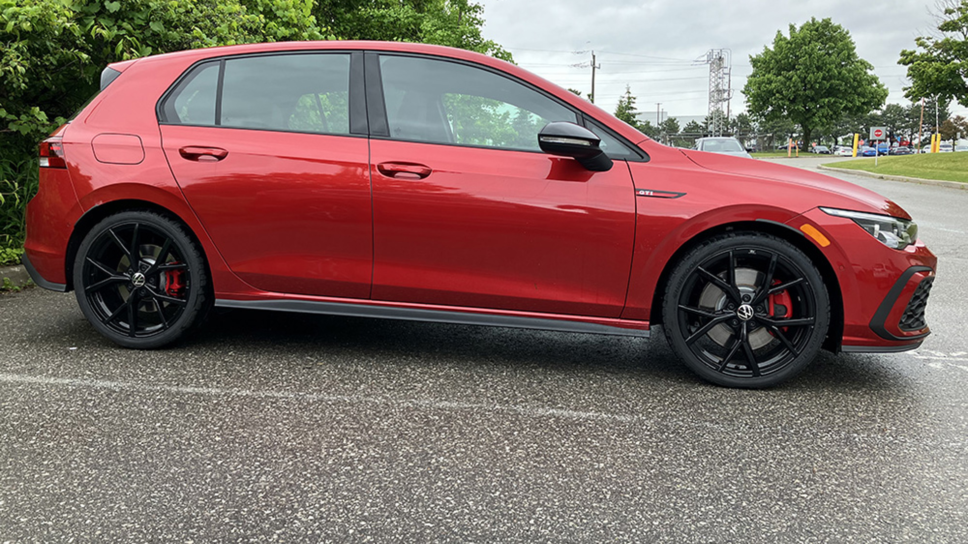 Side profile of a red Volkswagen Golf GTI parked in a parking lot.