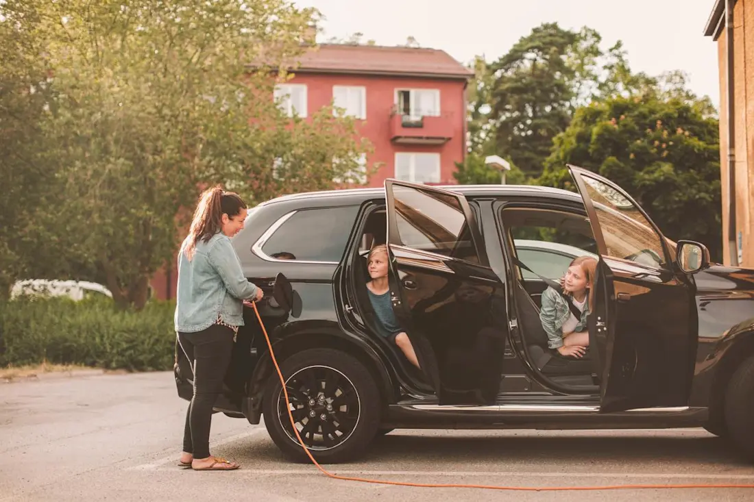 Woman charging her car while kids are sitting inside Woman charging her car while kids are sitting inside